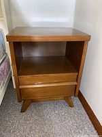 Full frontal view of the night table showing two drawers and open shelf under the top surface, placed on carpet.