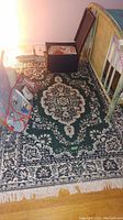 Large dark green decorative rug with white and black intricate pattern and fringe on floor under furniture