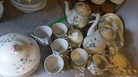 Full arrangement of tea and coffee set including cups, pots, and serving dishes showing floral pattern, rose-shaped lid knobs, and overall condition.