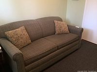 Front view of a two-seater sofa bed with two patterned throw pillows on each side
