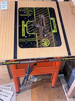 Full view of the Hirsch table saw showing wooden work surface, metal rails, central circular blade area with safety markings, and orange metal frame with power cord.
