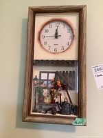Full view of the rectangular quartz wall clock with wooden frame, clock face on top and miniature garden scene below.