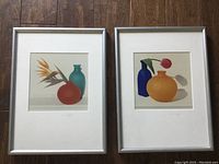 Two framed prints by Michael Stipek placed side by side on wooden floor, showing colorful stylized floral still life compositions.