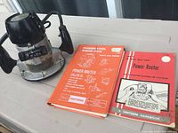 Photo showing the power router next to two manuals, placed on a table.