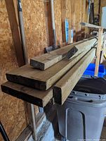 Photo shows ends of pressure treated lumber pieces, stacked horizontally indoors. Different sizes of lumber visible.