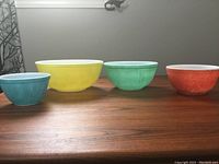 Photo showing the 4 Pyrex mixing bowls lined up from left to right: blue, yellow, green, orange. Shows relative size and color of each bowl.