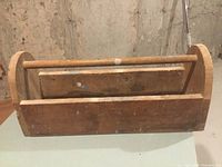 Front angle view of rustic wooden toolbox showing handle and curved sides