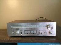 Front view of Akai AT-2600 stereo tuner receiver showing silver front panel with controls and meters
