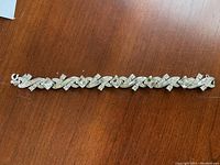 Full view of the silver-tone rhinestone bracelet with variously shaped rhinestones on a wooden surface.