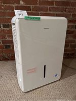 Front view of white Insignia dehumidifier showing water level window and brand name.
