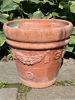Full view of the Italian terracotta planter with garland decorations outdoors, showing shape, size, and embossed design.