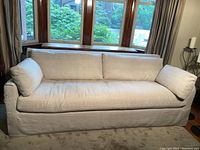 Front elevation of beige linen slipcovered sofa