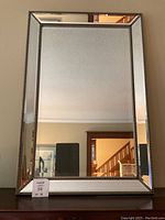 Full frontal view of the rectangular mirror mounted on a dresser, showing metal beaded border and beveled panels.