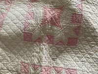 Close-up photo showing the pink and white patchwork floral design and detailed hand quilting stitches.