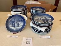 Stacked display of Royal Copenhagen Christmas plates, arranged in two stacks showing vintage and later production eras.