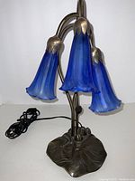 Front view of the vintage Art Deco blue glass tulip lamp showing three tulip-shaped shades and lily pad style metal base.