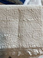 Close up of white needlepoint quilted fabric with lace trim