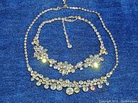 Two vintage rhinestone necklaces displayed on blue fabric, showing overall design and length.