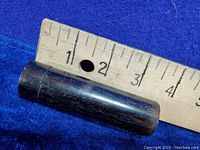 Cylindrical ebony wood hat pin box next to a ruler showing a length of approximately 3.25 inches.