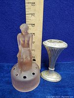 Pink frosted glass rose bowl centerpiece with seated nude figure and holes for flower arranging alongside the pewter posy holder vase, with a ruler for size reference.