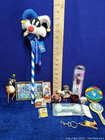 Wide shot of all vintage toys and figures with ruler for size reference on blue background
