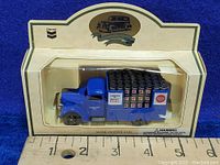 Side view of the diecast blue flat bed truck with miniature roof paint cans inside original packaging.