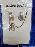 Photo of pendant necklace and earrings new in original packaging showing teardrop stones and crystal accents on gold-tone metal