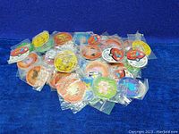 Assorted colorful Pokemon character pogs, new in plastic packaging, spread on blue fabric background.