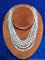 Front view of the 5 strand vintage necklace displayed on a brown stand showing tiered layered glass beads.