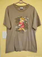 Full view of brown t-shirt showing the framed graphic design of Grumpy the dwarf on front.