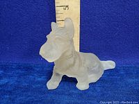 Frosted glass Scottish Terrier figurine against a blue background with a ruler showing height about 4 inches.