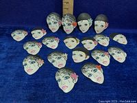 Overview of 18 vintage celluloid masks showing various pixie and mime faces with a measuring ruler for scale.