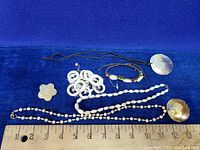 Image showing the jewelry pieces arranged with a ruler for size reference on a blue cloth.