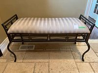 Frontal view of bench showing metal frame, cushion with striped pattern and round decorative details.