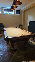 Front angle of pool table showing legs, rails and overhead lights