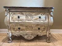 Front view of the dresser showing two large drawers with ornate carvings and decorative knobs, curved legs, and bottom decorative apron.