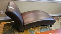 Side view of the brown leatherette lounge chair showing curved seat and backrest, wood veneer legs visible.