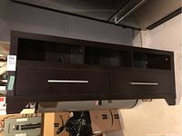 Full front view of dark brown faux wood media cabinet showing two drawers below two open shelves.