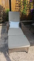 Front view of the wicker patio lounger with beige cushions and two beige pillows