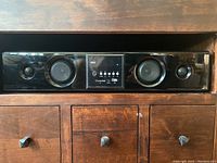Front view of the Pyle soundbar on wooden furniture, showing speakers and central control panel.