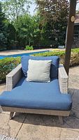 Front view of one chair showing blue seat and back cushions with a light grey throw pillow