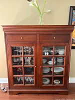 Full front view of Shermag wood and veneer china cabinet with glass doors and display shelves inside showing glassware and dishes.