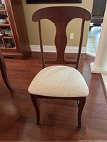Front view of one upholstered chair with curved wood back and cream patterned seat upholstery