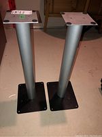 Pair of metal speaker stands with square bases and top plates.