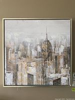 Full frontal image of the 19x19 textured cityscape print depicting a gray and white city skyline with gold paint accents, square shape, in a silver frame.