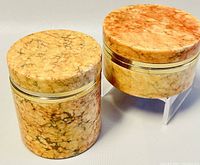 Two round polished marbled stone trinket boxes with gold-tone metal trim, shown closed side-by-side from slightly elevated angle.
