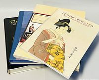 Three art reference books fanned out to show covers and thickness, featuring Asian and collectible art themes