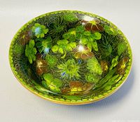 Top angled view of bowl showing the colorful floral cloisonné enamel decoration inside the bowl with green background and metal rim.