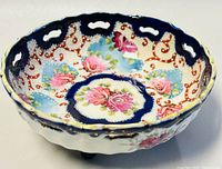 Angled top-down view showing interior floral design with pink roses, cobalt blue scalloped rim with raised dot detailing