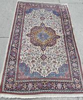 Full head-on view of entire rug laid flat on pavement showing central medallion and border patterns.